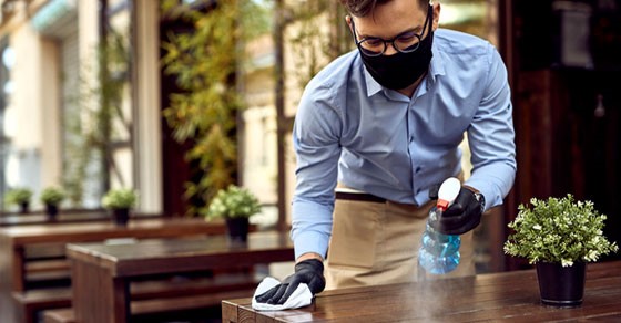 Man cleaning a table with a mask