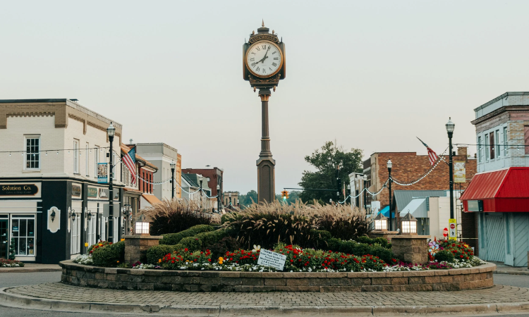 Town square in Columbiana, Ohio with central clock tower, landscaped roundabout, and surrounding storefronts
